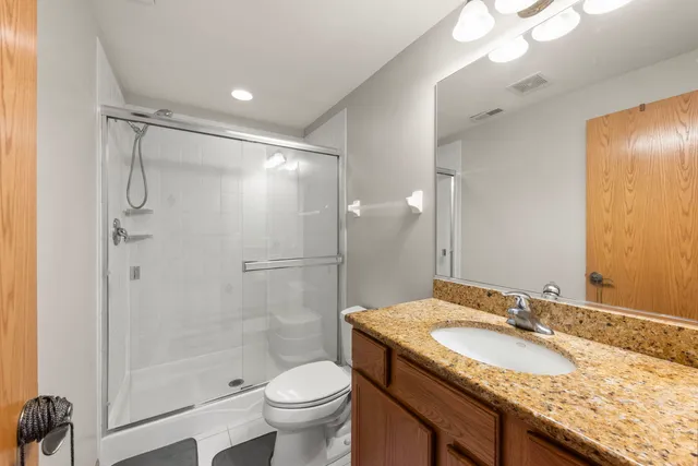 a bathroom with a granite countertop sink a toilet and shower