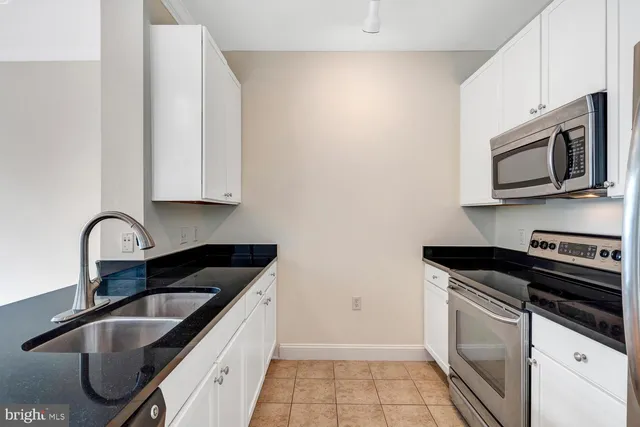 a kitchen with granite countertop a sink stainless steel appliances and cabinets