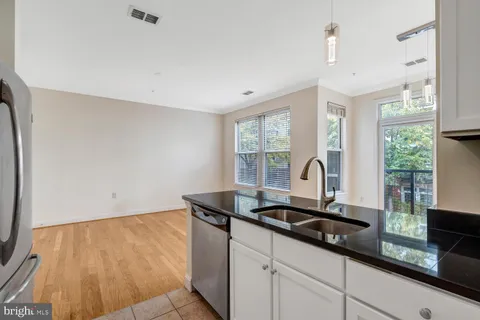 a kitchen with granite countertop a sink and a white cabinets