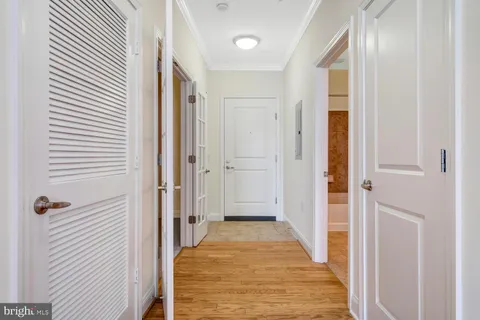 a view of a hallway with wooden floor and a bathroom