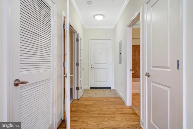 a view of a hallway with wooden floor and a bathroom