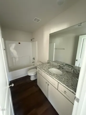 a bathroom with a granite countertop sink a toilet a mirror and shower