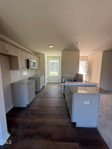 a large kitchen with stainless steel appliances a large counter top a stove a chimney a sink and a refrigerator