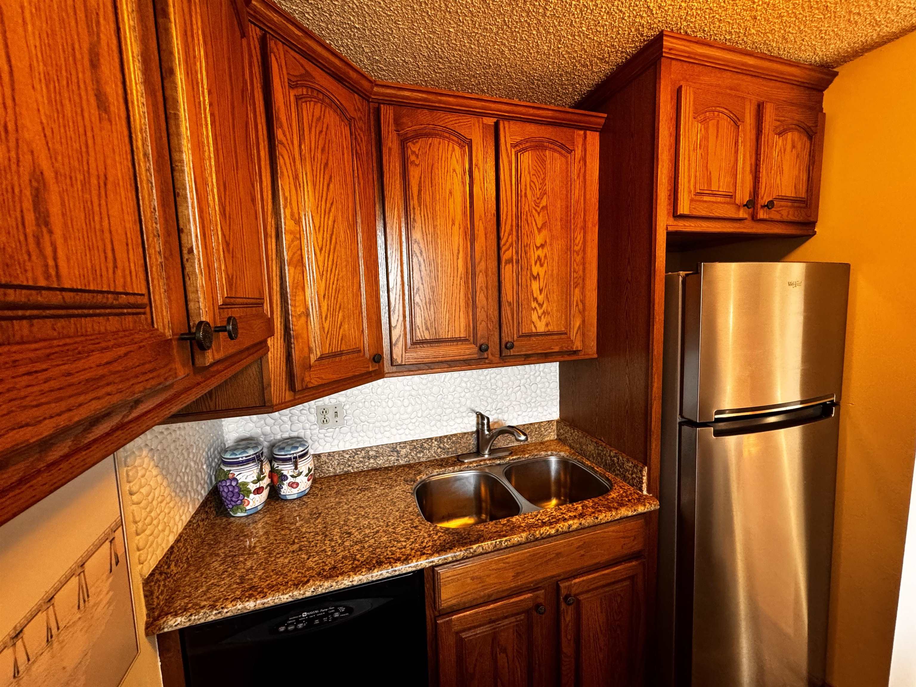 4310 Lower Honoapiilani Road, Unit 315 Lahaina, HI 96761 - Photo 5 of 20 a kitchen with granite countertop a refrigerator a sink and cabinets