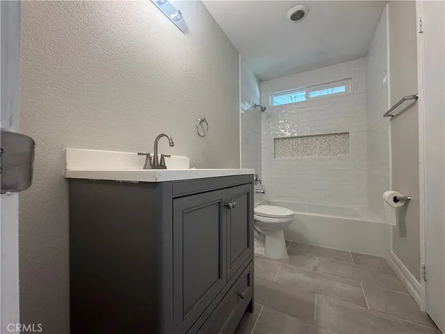 a bathroom with a granite countertop sink a toilet and shower