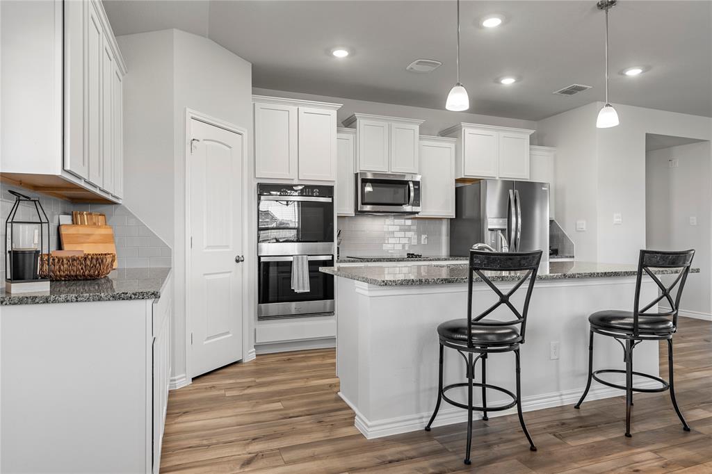 10761 Chesson Flts Drive Waco, TX 76708 - Photo 12 of 30 a kitchen with stainless steel appliances kitchen island granite countertop a refrigerator a stove top oven a sink dishwasher and white cabinets with wooden floor