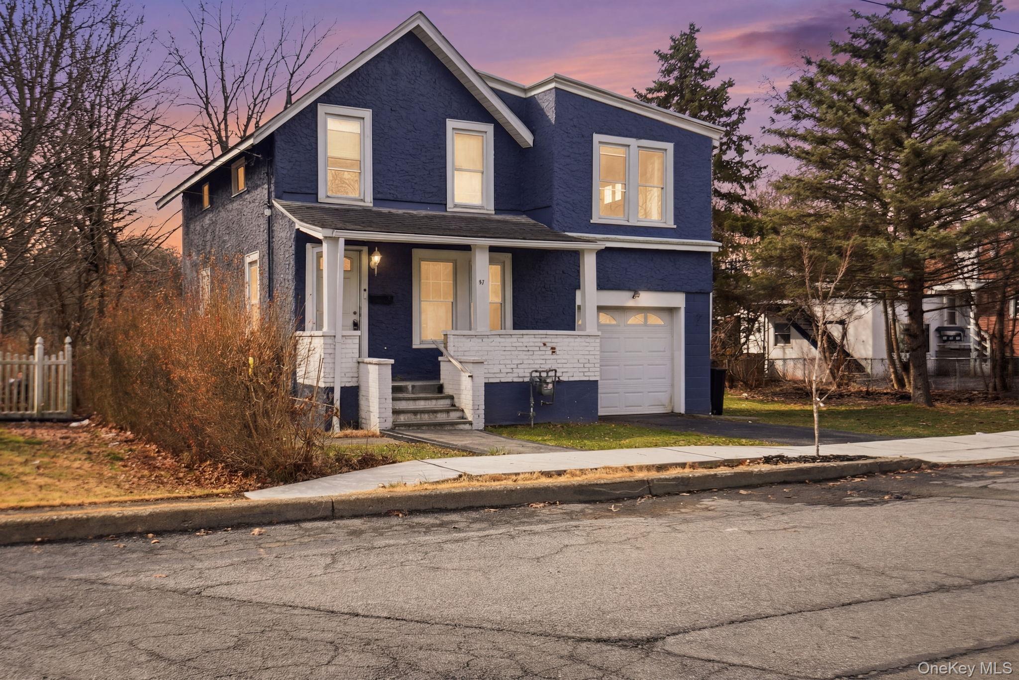View of front of house featuring brick siding, covered porch, an attached garage, and asphalt driveway