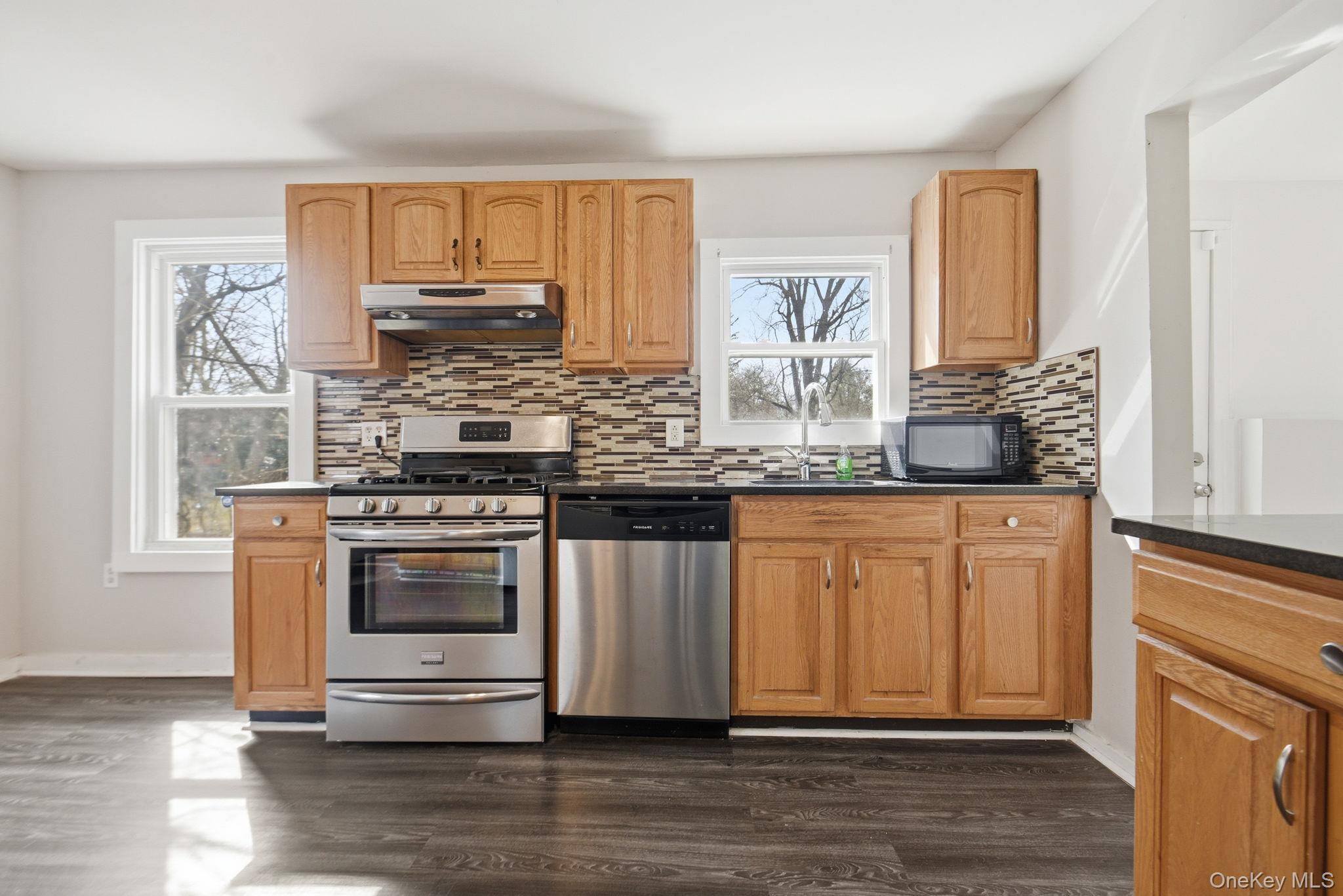 97 Maple Street Newburgh, NY 12550 - Photo 11 of 31 Kitchen with stainless steel appliances, dark wood-style flooring, backsplash, and dark stone countertops
