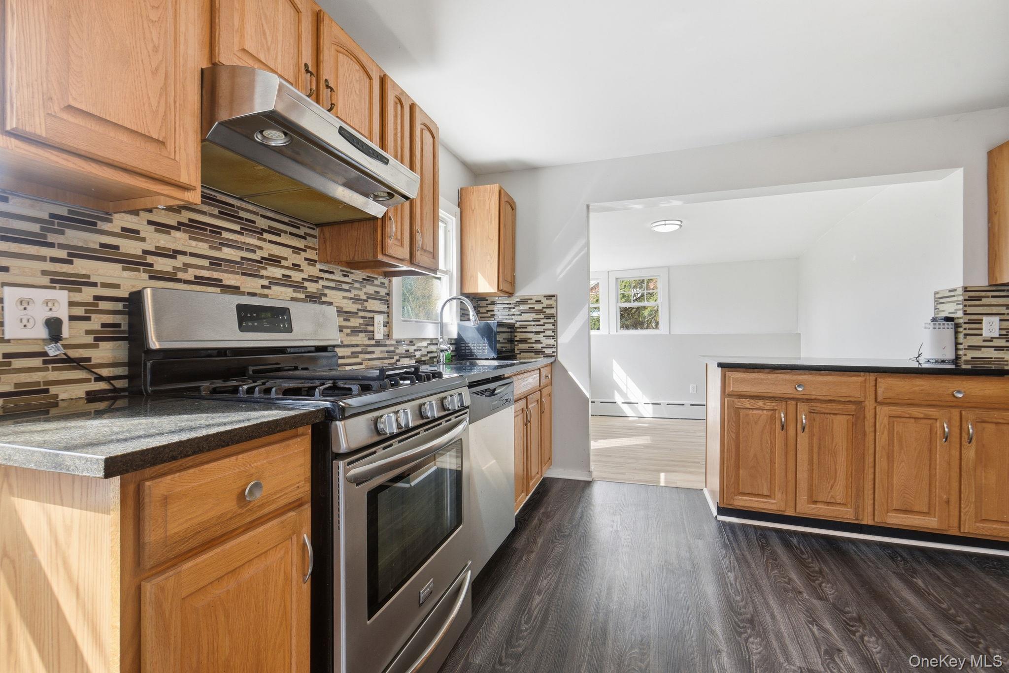 97 Maple Street Newburgh, NY 12550 - Photo 12 of 31 Kitchen featuring stainless steel appliances, tasteful backsplash, dark wood-type flooring, and dark stone countertops