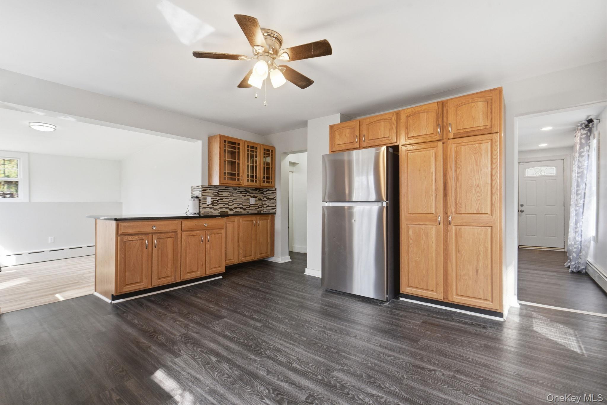 97 Maple Street Newburgh, NY 12550 - Photo 13 of 31 Kitchen with glass fronted cabinets, freestanding refrigerator, a ceiling fan, and dark wood-style flooring