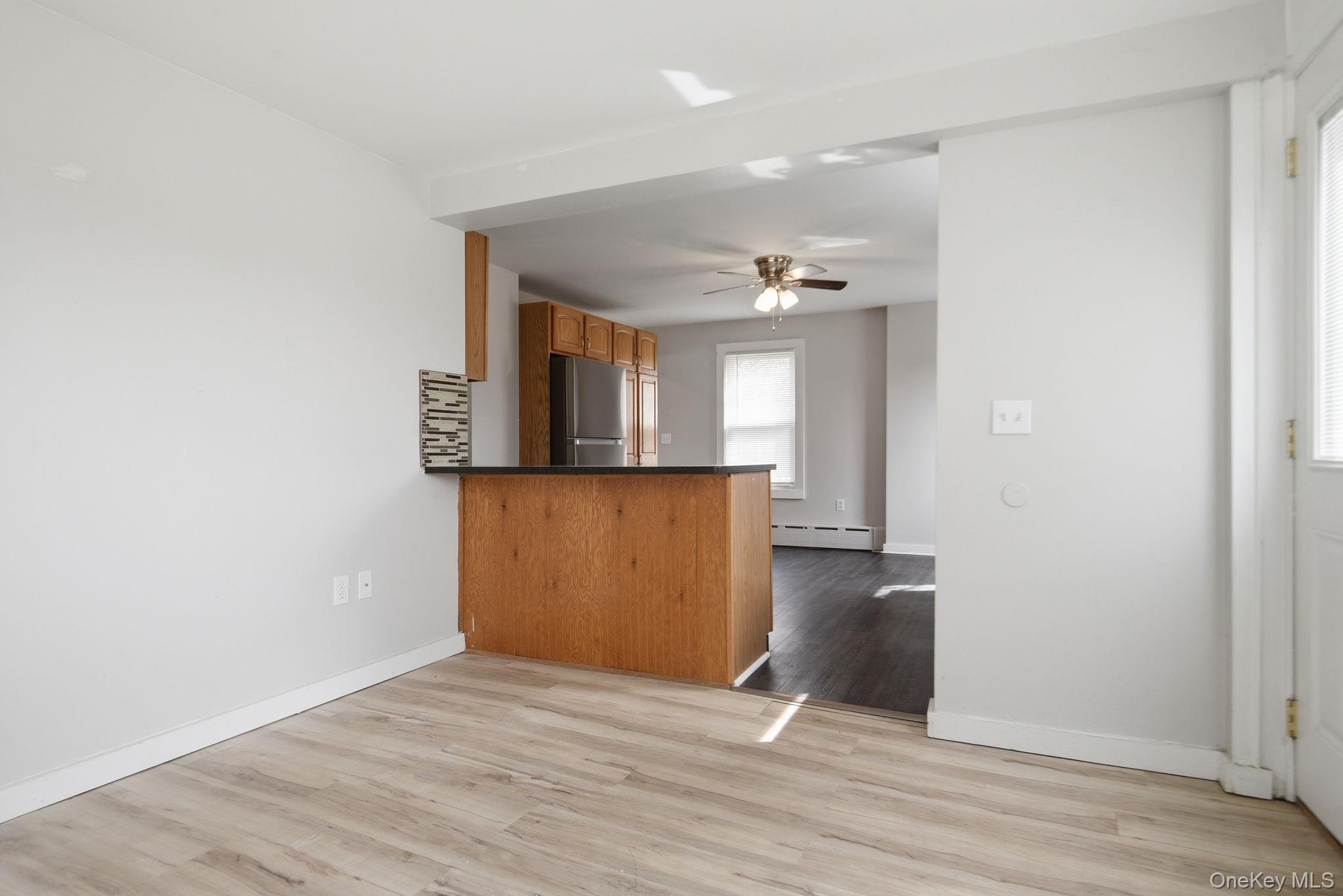 97 Maple Street Newburgh, NY 12550 - Photo 16 of 31 Kitchen featuring a peninsula, light wood-style floors, a ceiling fan, dark countertops, and freestanding refrigerator