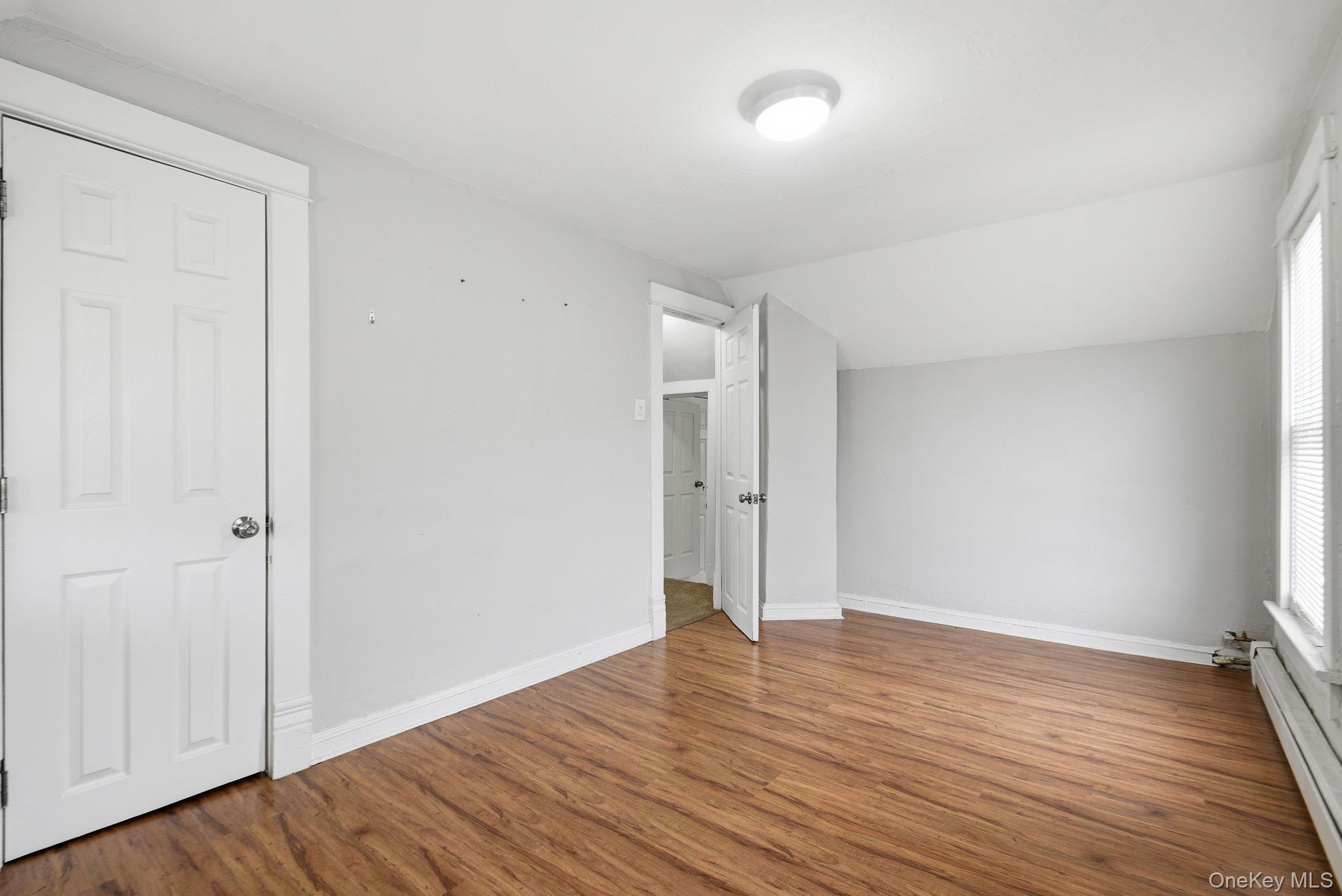 97 Maple Street Newburgh, NY 12550 - Photo 19 of 31 Unfurnished bedroom with lofted ceiling, baseboard heating, and dark wood-type flooring