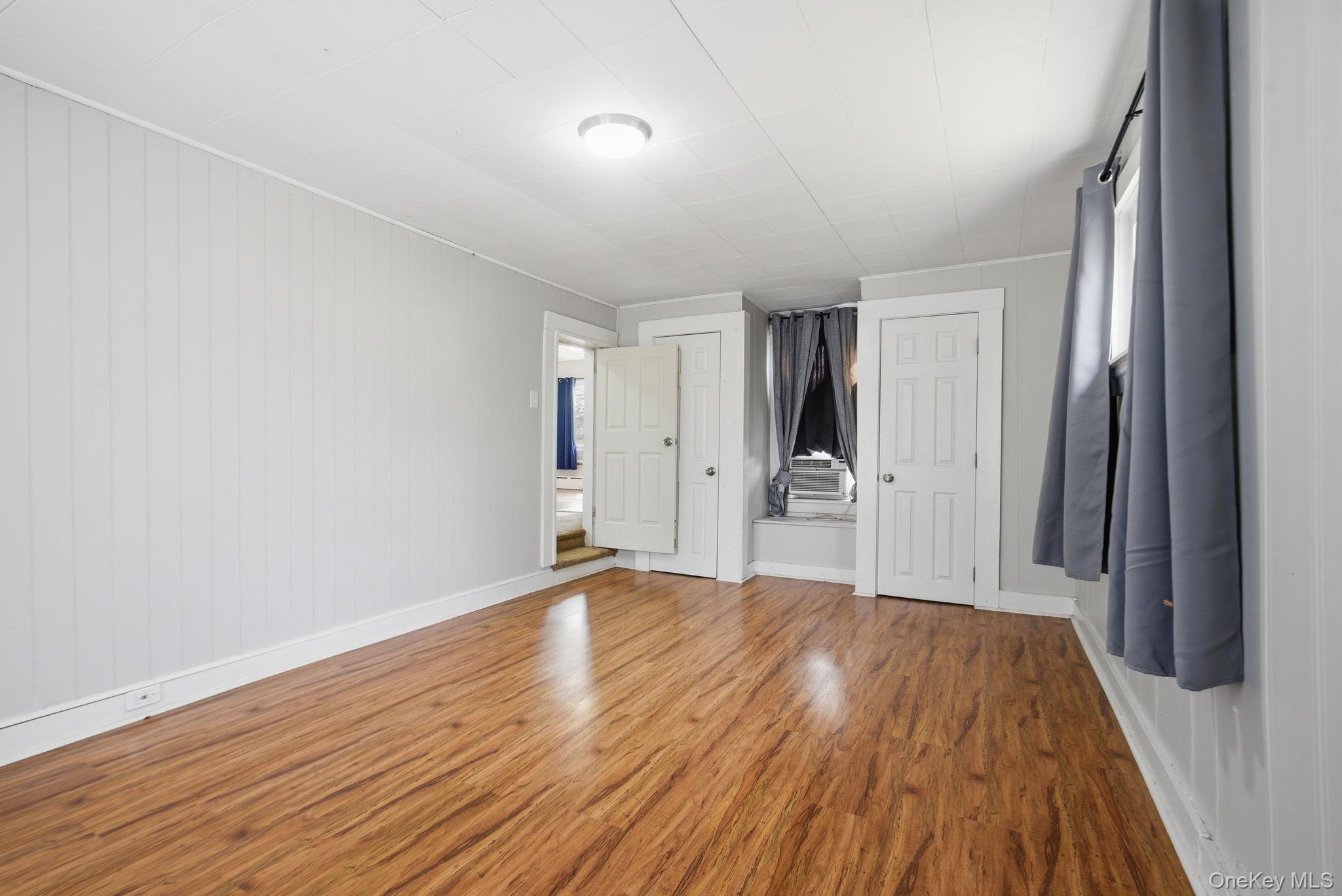 97 Maple Street Newburgh, NY 12550 - Photo 21 of 31 Unfurnished bedroom with a closet, light wood finished floors, and wood walls