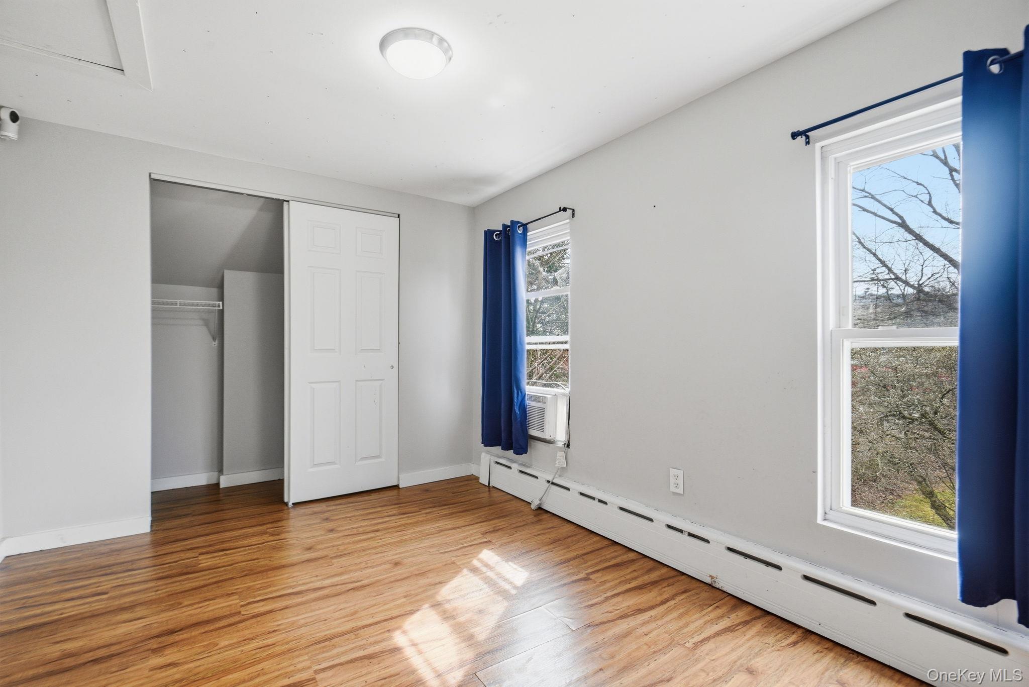 97 Maple Street Newburgh, NY 12550 - Photo 22 of 31 Unfurnished bedroom featuring baseboard heating, light wood-type flooring, a closet, and cooling unit