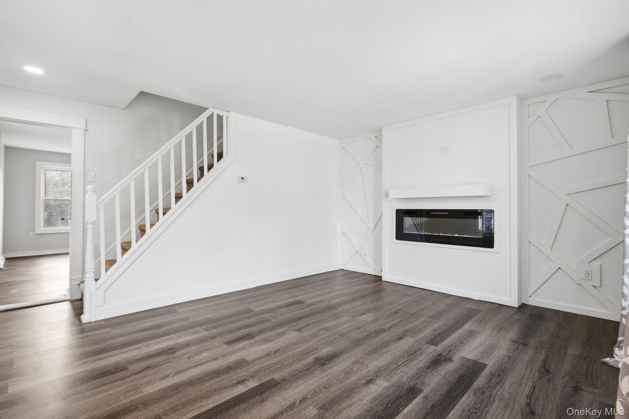 97 Maple Street Newburgh, NY 12550 - Photo 7 of 31 Unfurnished living room with a glass covered fireplace, dark wood-style flooring, and recessed lighting