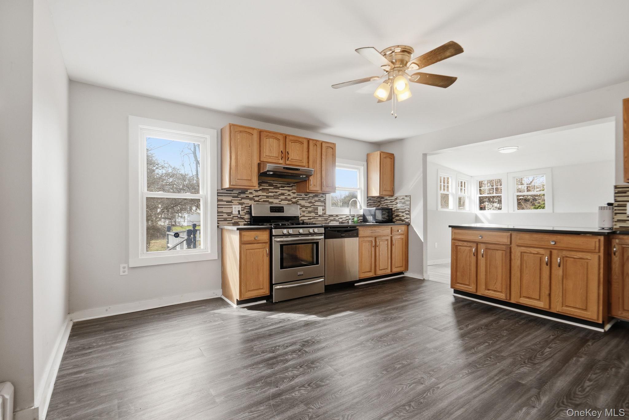 97 Maple Street Newburgh, NY 12550 - Photo 9 of 31 Kitchen with stainless steel appliances, a ceiling fan, decorative backsplash, and dark wood-type flooring