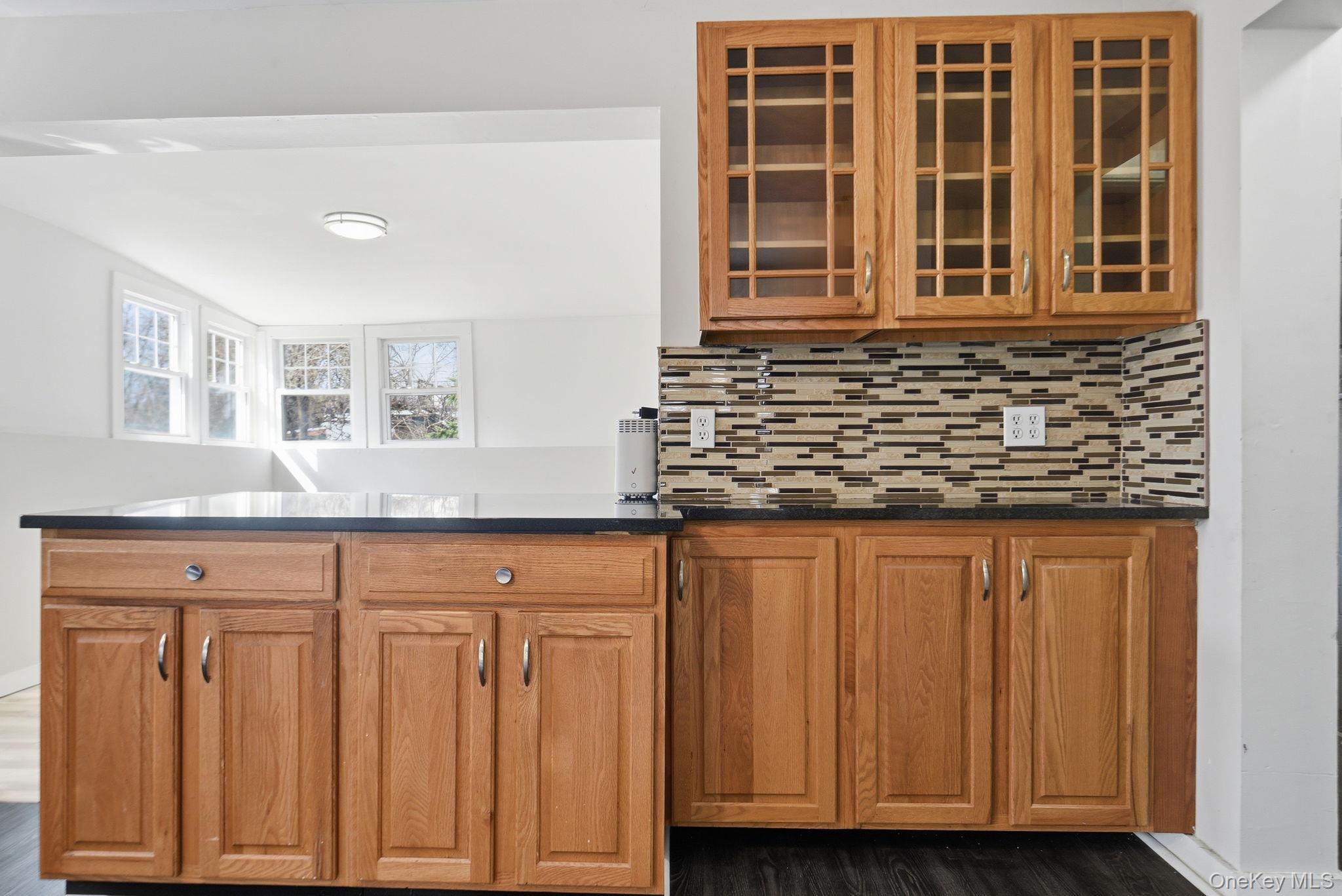97 Maple Street Newburgh, NY 12550 - Photo 10 of 31 Kitchen with glass fronted cabinets, decorative backsplash, and wood finish cabinetry