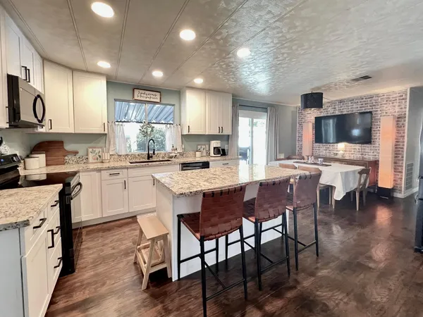 a kitchen with stainless steel appliances granite countertop a table chairs sink refrigerator and cabinets