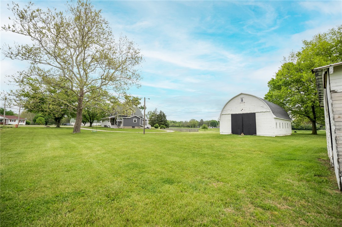 190 Swailes Road Troy, OH 45373 - Photo 72 of 82 Expansive green yard with a classic barn and mature trees under a bright sky.