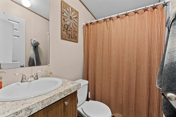 a bathroom with a granite countertop toilet sink and mirror