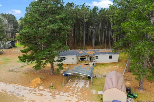 an aerial view of a house with swimming pool and large trees