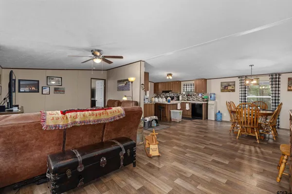 a living room with furniture a wooden floor and kitchen view