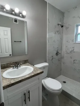 a bathroom with a granite countertop toilet sink and shower