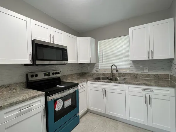 a kitchen with granite countertop white cabinets sink and stainless steel appliances