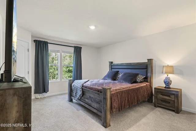 a bedroom with a bed table and a flat tv screen