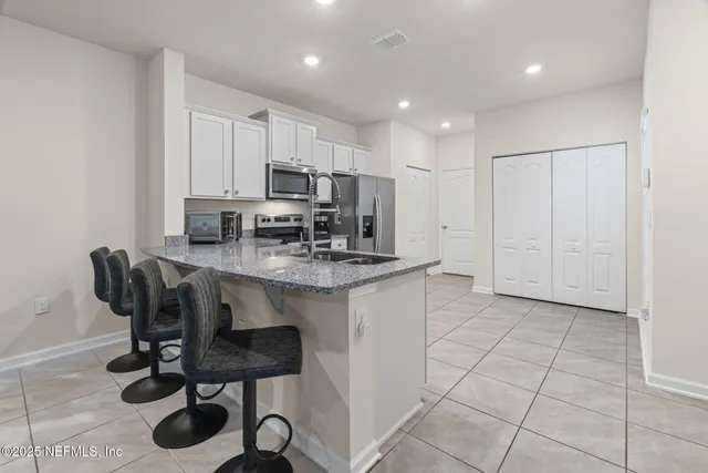 a kitchen with kitchen island granite countertop a stove a sink a counter space and cabinets