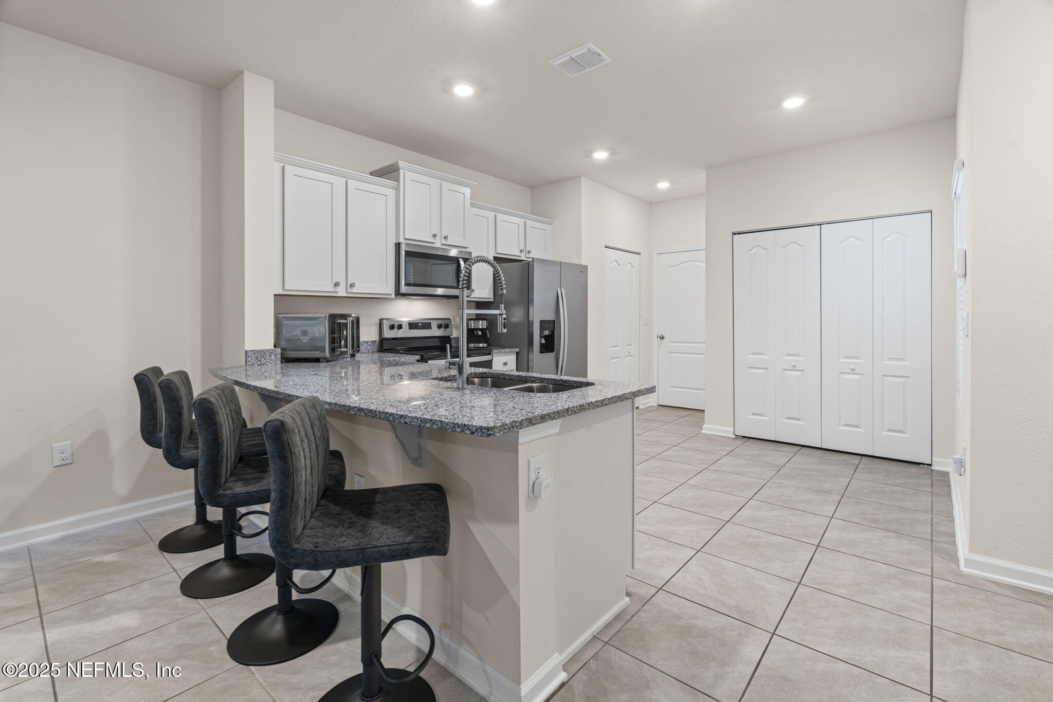 263 Talulla Trail St. Augustine, FL 32095 - Photo 5 of 32 a kitchen with kitchen island granite countertop a stove a sink a counter space and cabinets