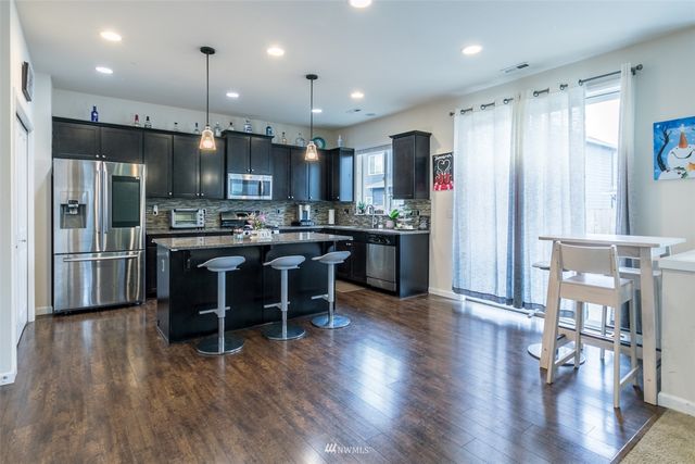 a kitchen with stainless steel appliances granite countertop a table chairs refrigerator and sink