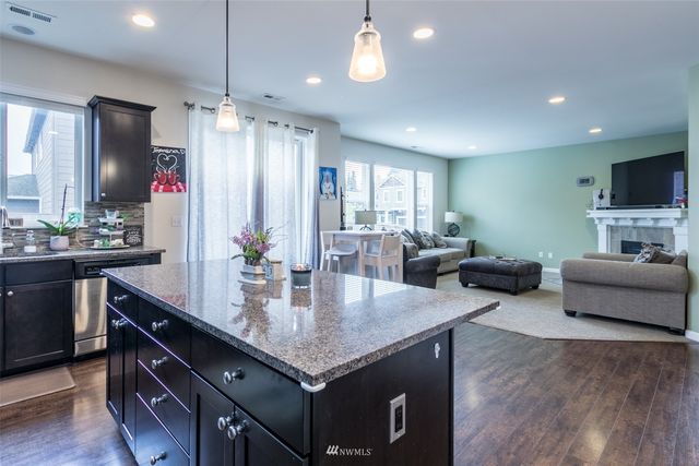a living room with granite countertop furniture a sink a faucet a flat screen tv and kitchen view