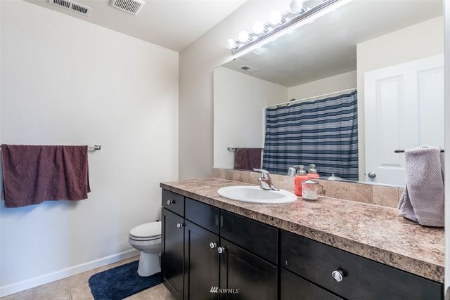 a bathroom with a granite countertop sink a toilet and a large mirror