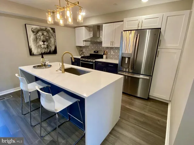 a kitchen with stainless steel appliances a refrigerator a sink a stove a table and chairs