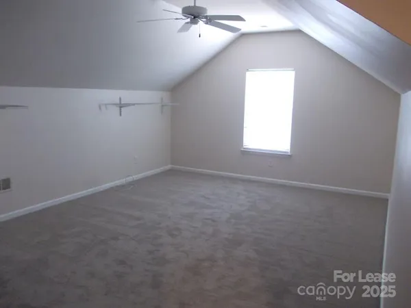 an empty room with a chandelier fan and windows