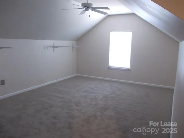 an empty room with a chandelier fan and windows
