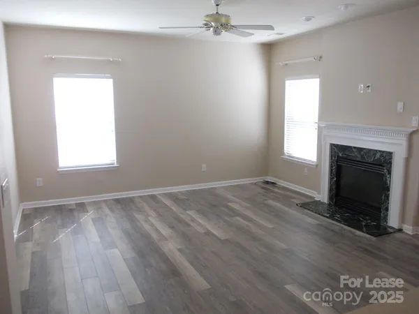 an empty room with wooden floor a fireplace and windows
