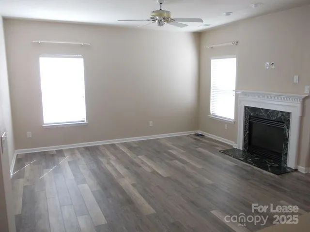 an empty room with wooden floor a fireplace and windows