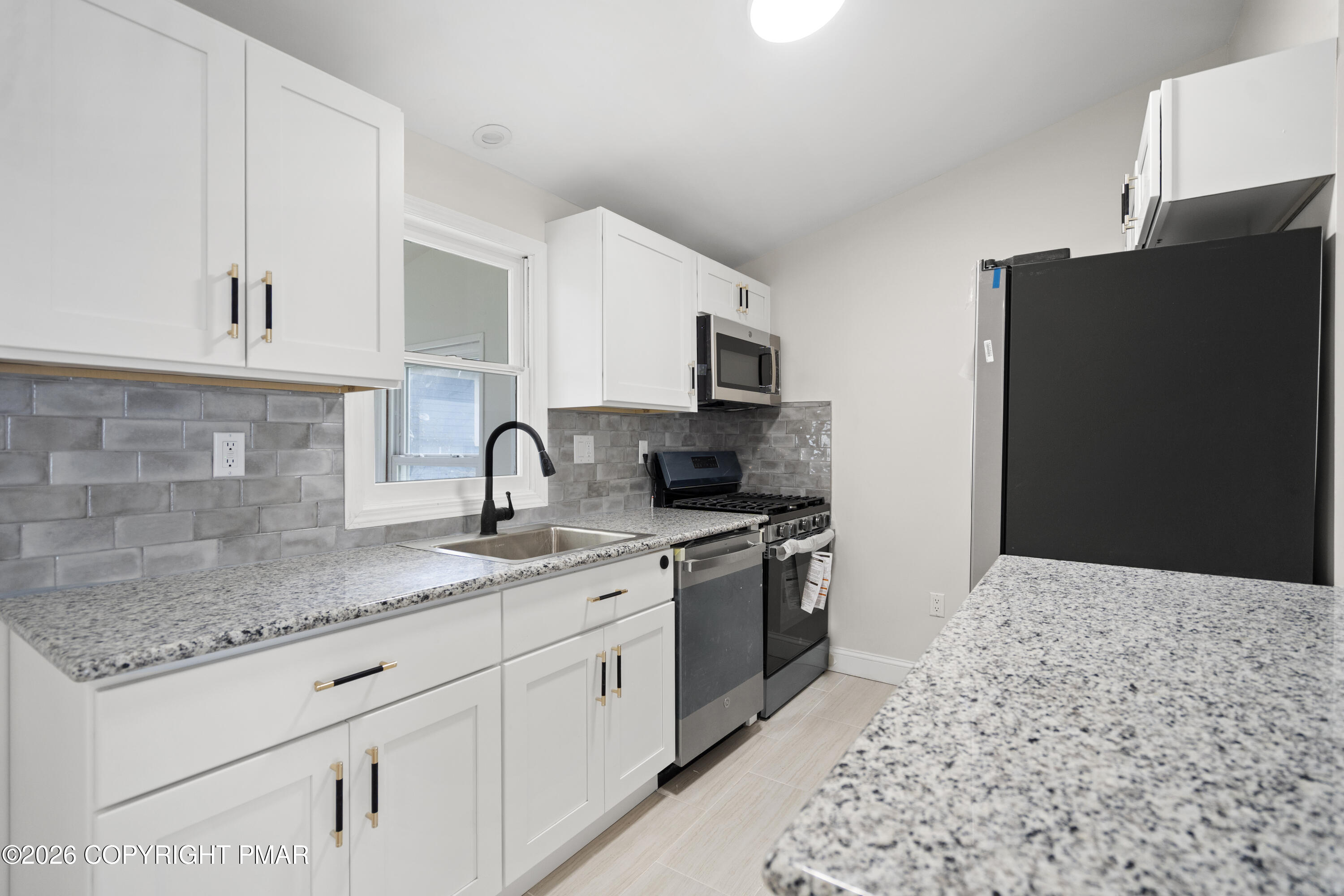 605 5th Street Matamoras, PA 18336 - Photo 7 of 27 a kitchen with granite countertop a sink stainless steel appliances and white cabinets