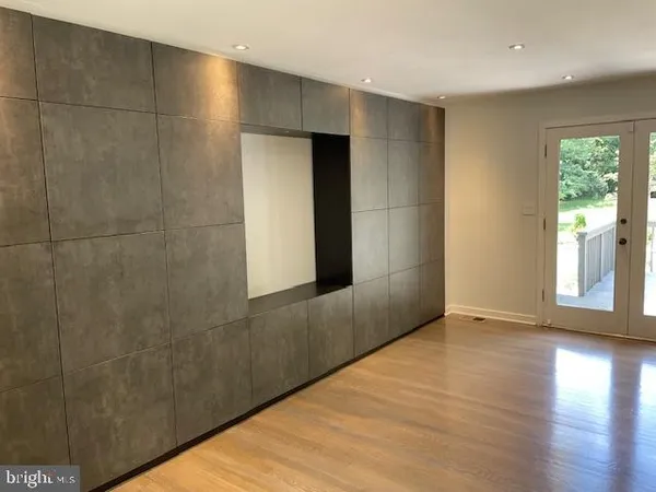 an empty room with wooden floor chandelier and windows