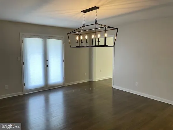 an empty room with wooden floor and chandelier