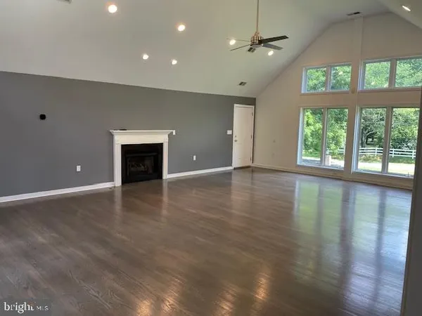 an empty room with wooden floor chandelier and windows