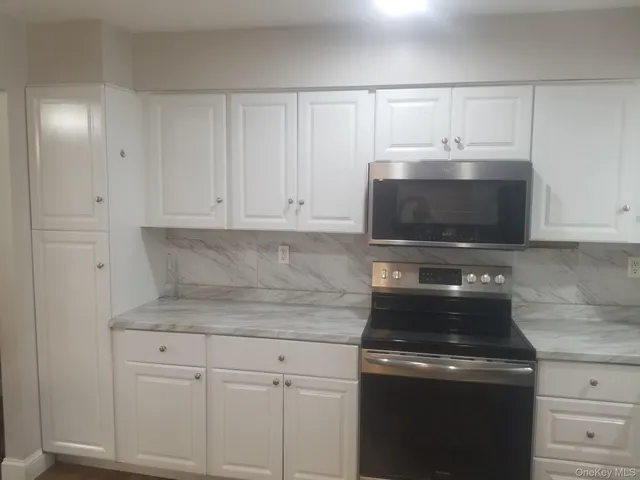 a kitchen with white cabinets and stainless steel appliances