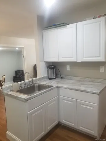 a kitchen with white cabinets and sink
