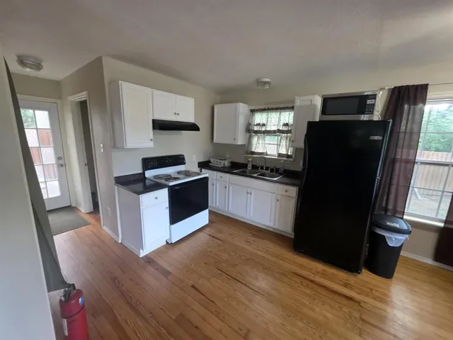 a kitchen with granite countertop stainless steel appliances a refrigerator cabinets and wooden floor