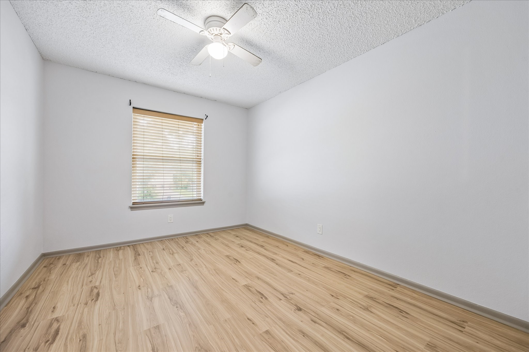 206 Lockett Street Brenham, TX 77833 - Photo 9 of 12 an empty room with wooden floor chandelier fan and windows