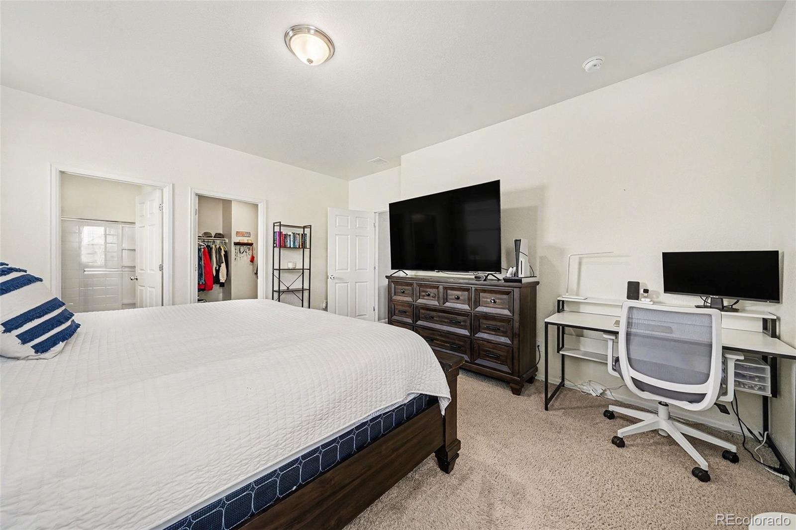 910 Pierson Court Windsor, CO 80550 - Photo 16 of 42 a bedroom with a bed and a flat screen tv