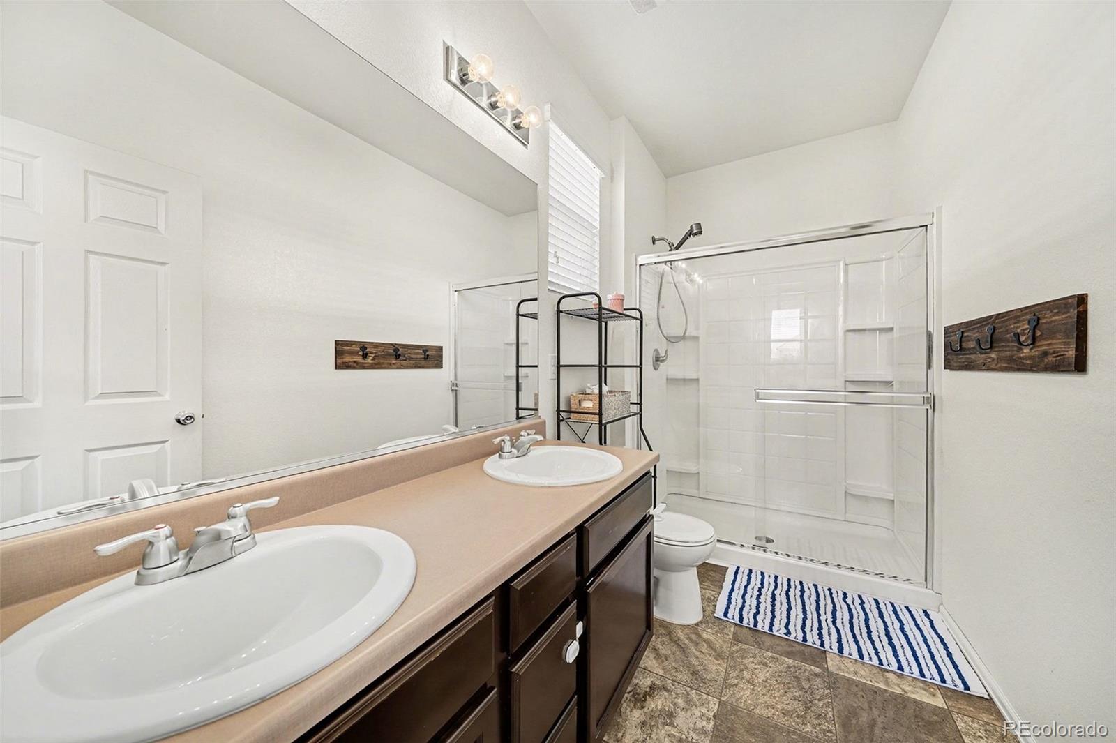 910 Pierson Court Windsor, CO 80550 - Photo 17 of 42 a bathroom with a sink double vanity granite tub shower and a mirror