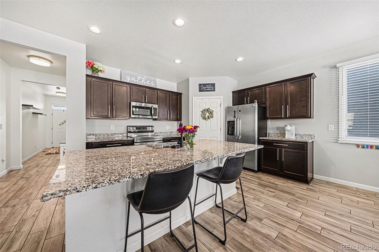 910 Pierson Court Windsor, CO 80550 - Photo 6 of 42 a kitchen with stainless steel appliances granite countertop a stove top oven a sink dishwasher a refrigerator and a oven